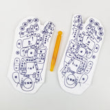 White cotton Massage Socks featuring detailed black reflexology charts printed on the soles with an included yellow plastic massage stick for foot acupressure therapy.