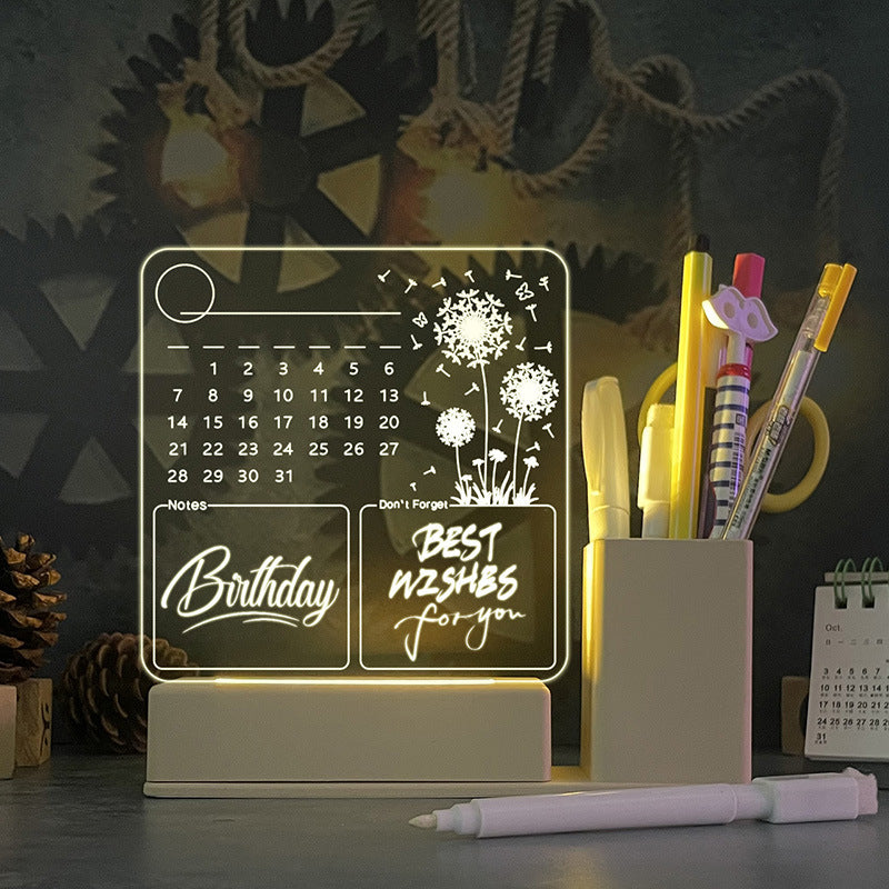 Acrylic calendar memo board with LED night light and dandelion design on desk with pen and USB base