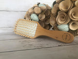 Natural wooden detangling hair brush with bamboo bristles and rubber cushioning for gentle, static-free styling
